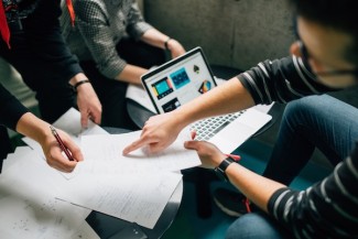 People sitting in a group around a computer with notes 