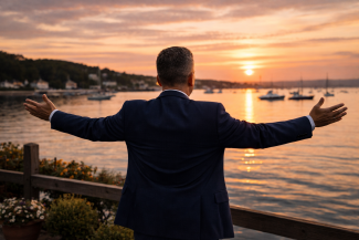 Silhouette of a man overlooking Oyster Bay harbor at sunset representing Oren Ziv community leadership in New York